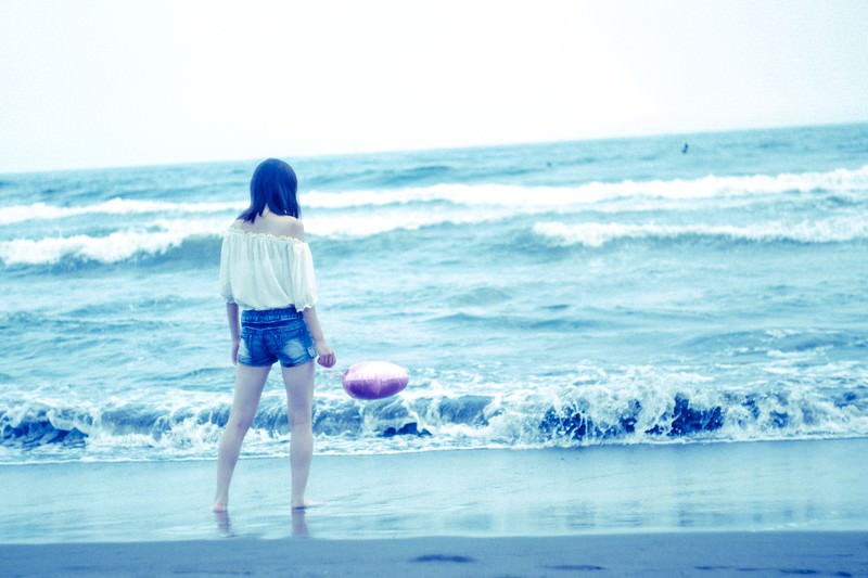 波打ち際で海を見つめる娘。