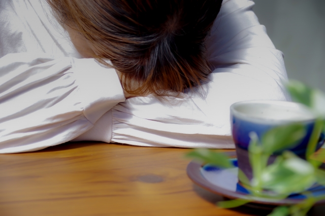 頭を抱えてうつむく女性のイメージ