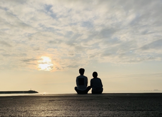 夕日を見つめる、若いカップルの後ろ姿