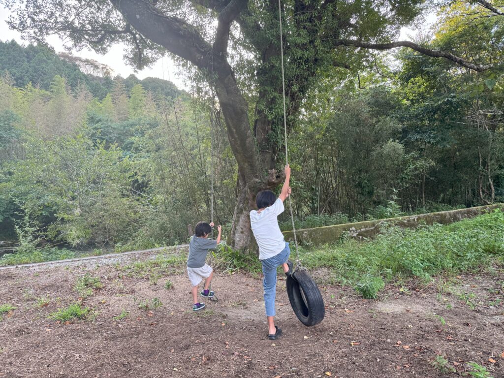古いタイヤブランコで遊ぶ子供たち。「ロープ長すぎー」とちょっぴり不満そう。