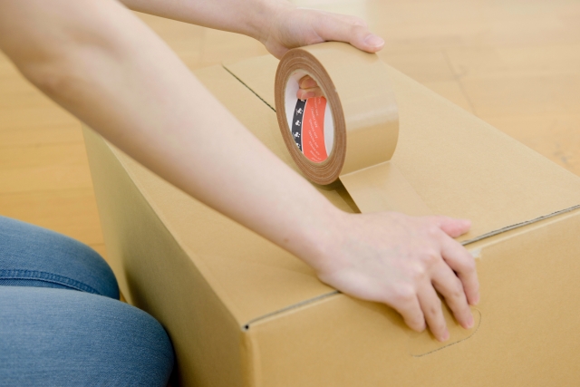 段ボールに荷物を詰める女性の手元画像